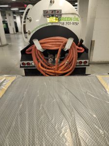 A green oil truck picking up waste oil from the world trade center in nyc so they can stay compliant with local fire safety laws.